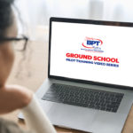 woman looking at computer monitor with ground school logo
